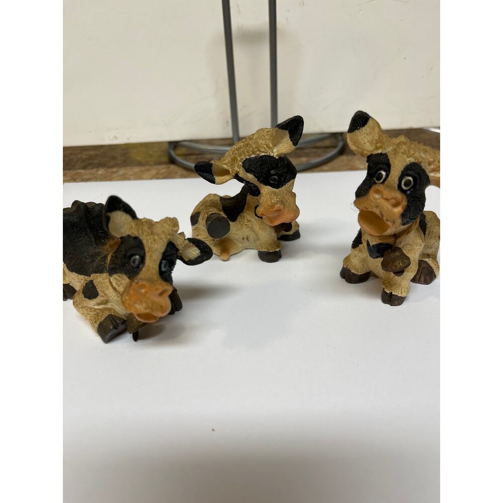 Three Holstein cow figurines with bells